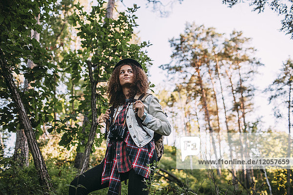 Porträt eines jungen Mädchens mit Kamera und Rucksack in der Natur