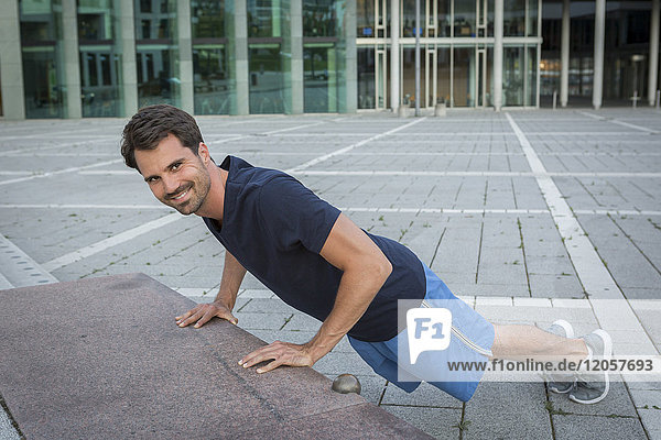 Jogger training in the city  doing push ups on a stair