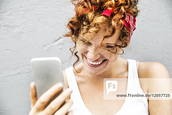 Fröhliche rothaarige Frau mit Handy