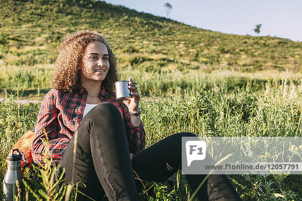 Teenage girl with thermos flask having a rest in nature