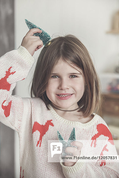 Porträt eines lächelnden Mädchens mit Miniatur-Weihnachtsbäumen