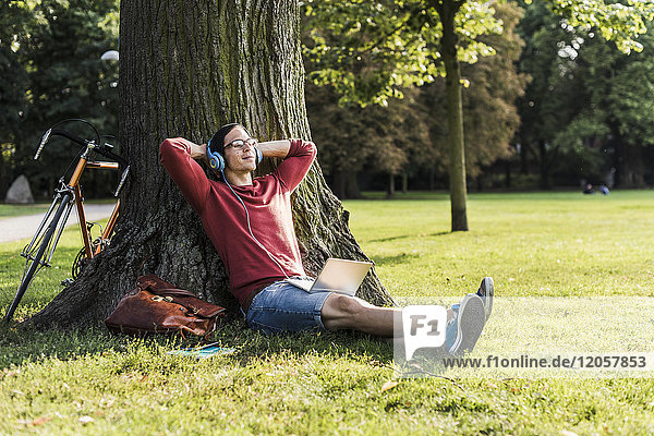 Mann mit Laptop und Kopfhörer entspannt im Park