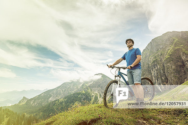 Germany  Bavaria  Pfronten  man with mountain bike on alpine meadow near Aggenstein