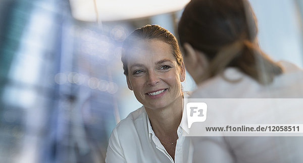 Lächelnde Geschäftsfrau hört einem Kollegen zu