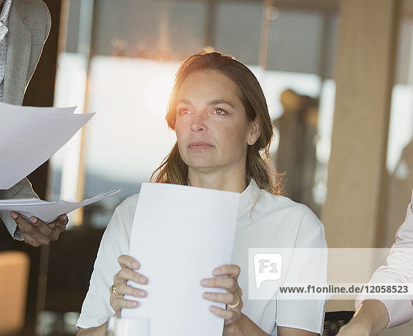 Ernste  nachdenkliche Geschäftsfrau mit Papierkram  die im Büro wegschaut