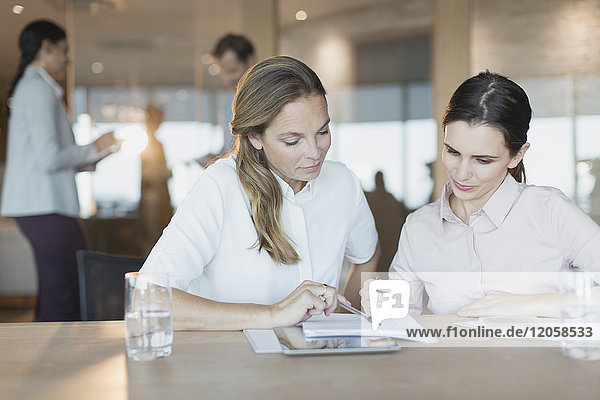 Businesswomen reviewing paperwork in conference room meeting