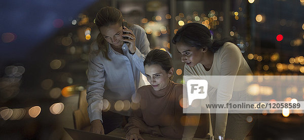Businesswomen working late at laptop in office at night
