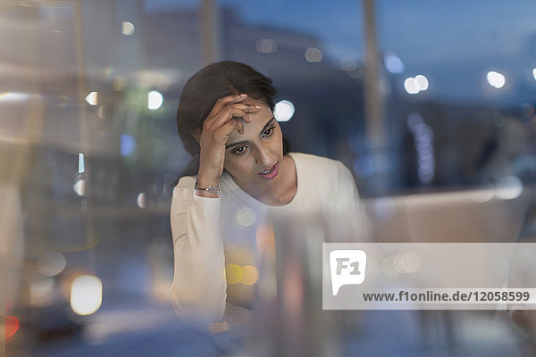 Müde Geschäftsfrau  die nachts im Büro am Laptop arbeitet