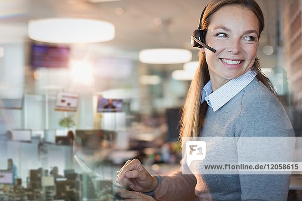 Lächelnde Geschäftsfrau mit Headset bei der Arbeit im Büro