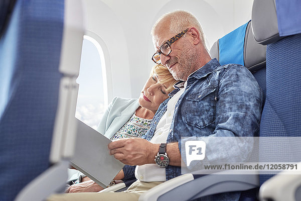 Liebevolles reifes Paar beim Schlafen und Lesen im Flugzeug