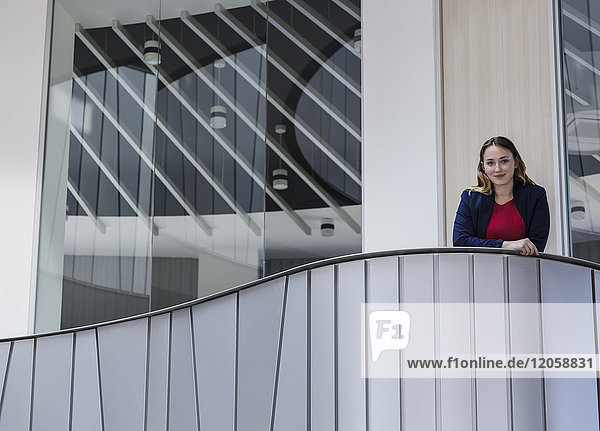 Porträt einer lächelnden  selbstbewussten Geschäftsfrau auf dem modernen Bürobalkon