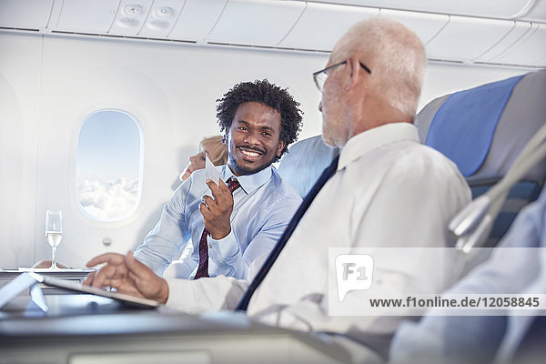 Lächelnde Geschäftsleute beim Austausch von Visitenkarten im Flugzeug