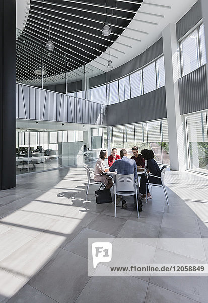 Geschäftsleute treffen sich am Tisch im modernen Büroatrium