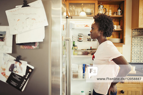 Hungrige Frau blickt in den Kühlschrank in der Küche