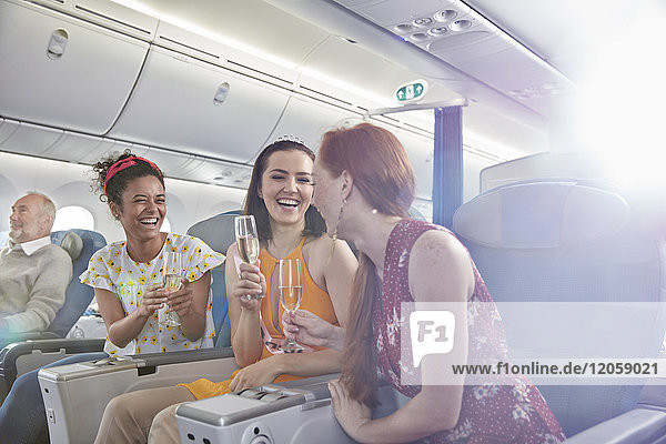 Junge Freundinnen trinken Champagner in der ersten Klasse im Flugzeug