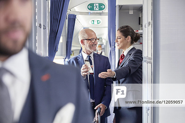 Flugbegleiterin hilft Geschäftsmann mit digitaler Bordkarte im Flugzeug