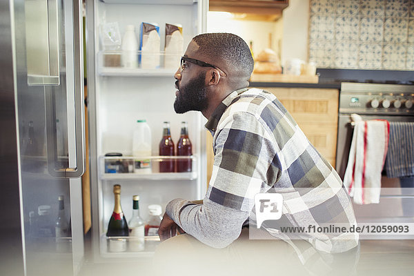 Hungriger Mann blickt in den Kühlschrank in der Küche