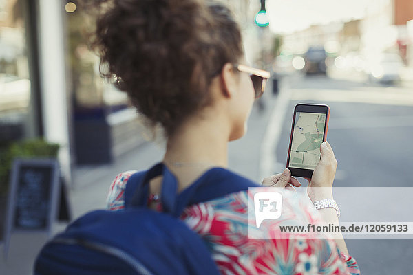 Junge Touristin mit Rucksack mit GPS auf dem Smartphone auf der Stadtstraße