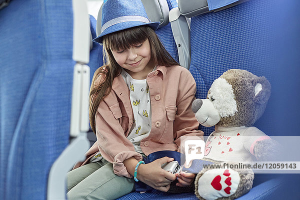 Sicherheitsgurt für Mädchen am Plüschtier im Flugzeug