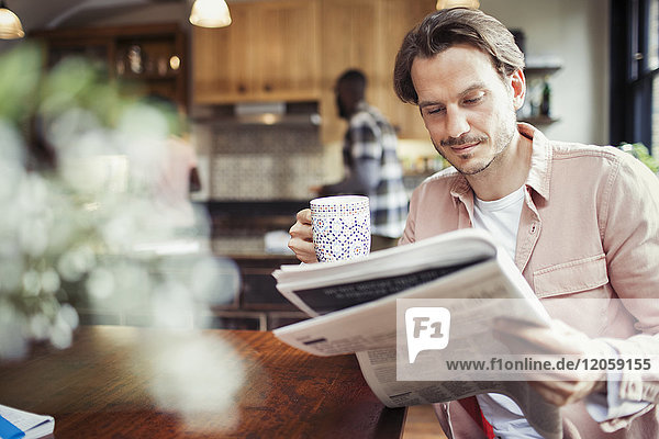 Mann trinkt Kaffee und liest Zeitung in der Küche