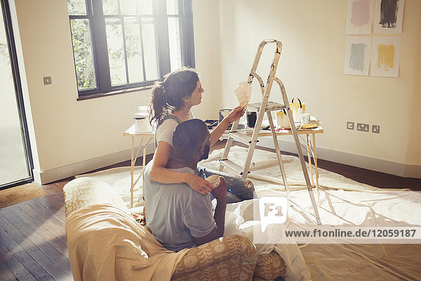 Junges Paar beim Betrachten von Farbmustern  Malerei im Wohnzimmer