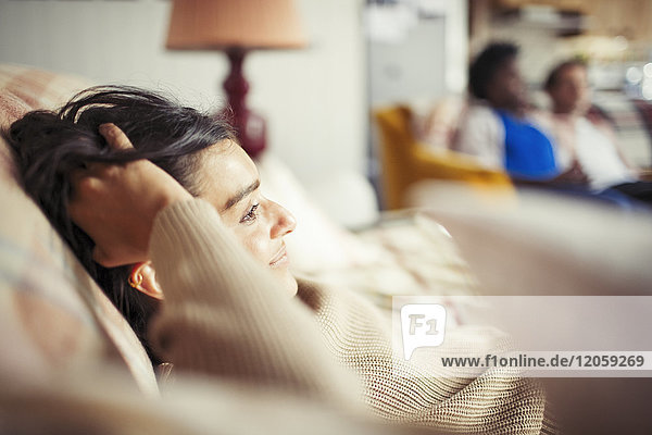 Junge Frau entspannt mit der Hand im Haar auf dem Sofa