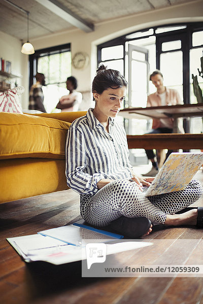 Female freelancer working at laptop on living room floor
