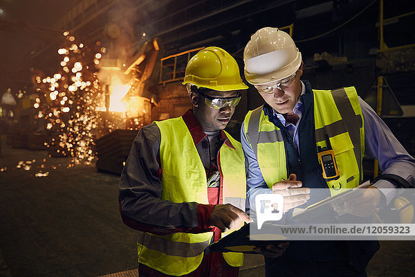 Stahlarbeiter mit digitalen Tabletten im Stahlwerk