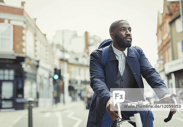 African businessman commuting  riding bicycle on urban street