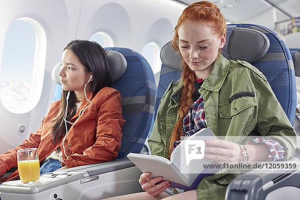 Junge Frau liest Buch im Flugzeug