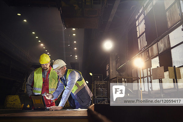 Stahlarbeiter mit Laptop im Stahlwerk