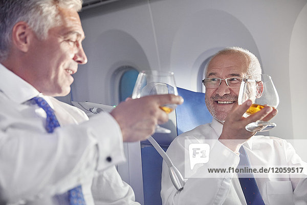 Geschäftsmann röstet Whiskygläser in der ersten Klasse im Flugzeug