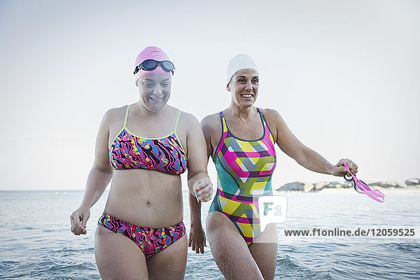 Smiling female open water swimmers wading in ocean