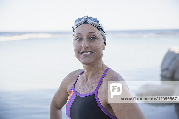 Portrait lächelnde  selbstbewusste Schwimmerin am Meer