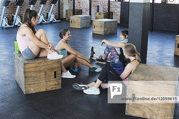 Junge Frauen beim Sprechen und Ausruhen im Fitnessstudio