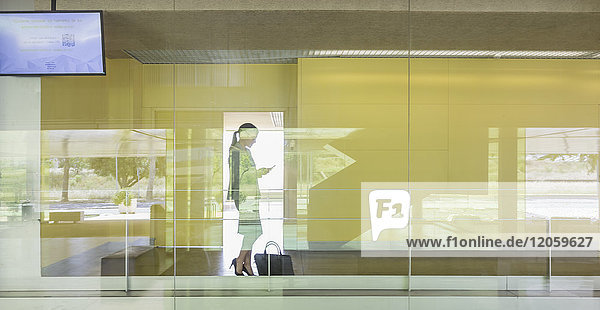 Silhouette Geschäftsfrau SMS mit Smartphone im modernen Bürofenster