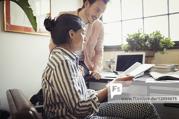 Geschäftsmann und Geschäftsfrau beim Durchsehen und Besprechen von Papierkram im Büro