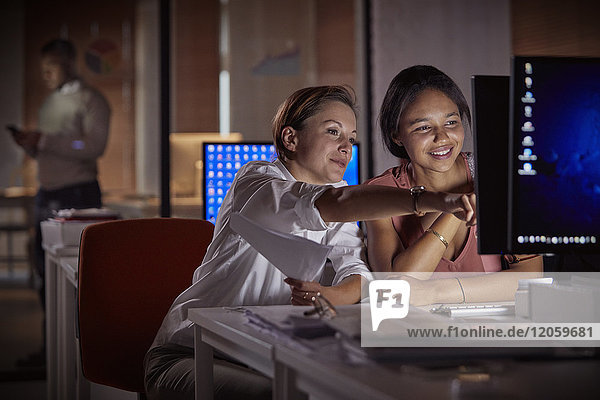 Weibliche Geschäftsfrauen arbeiten nachts spät am Computer im dunklen Büro.