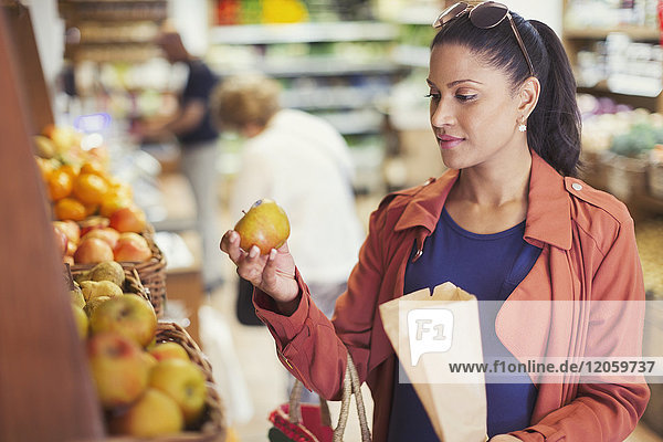 Frau einkaufen,  Apfel im Lebensmittelgeschäft prüfen