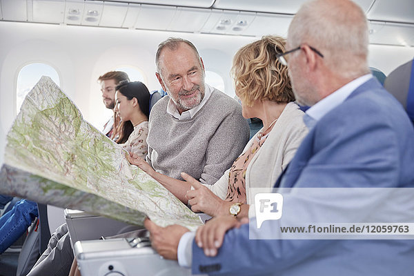Reife Freunde beim Betrachten der Karte im Flugzeug