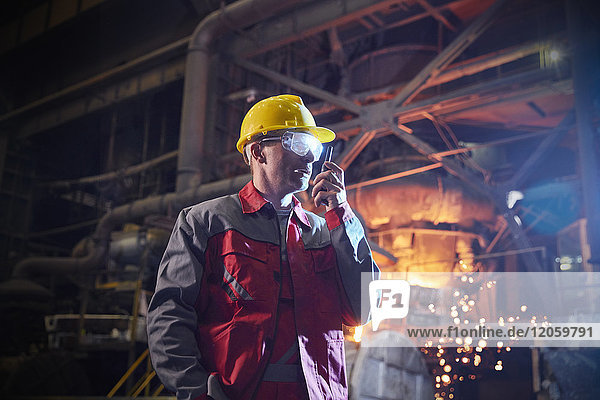 Stahlarbeiter im Gespräch  mit Walkie-Talkie im Stahlwerk