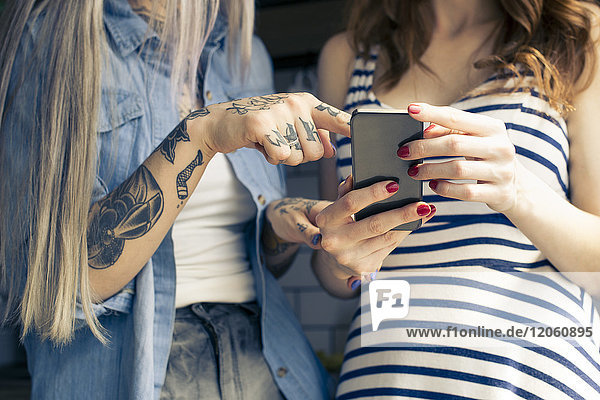 Frauen  die zusammen Smartphone benutzen  beschnitten