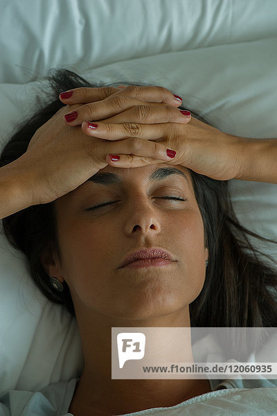 Woman lying in bed with hands on forehead