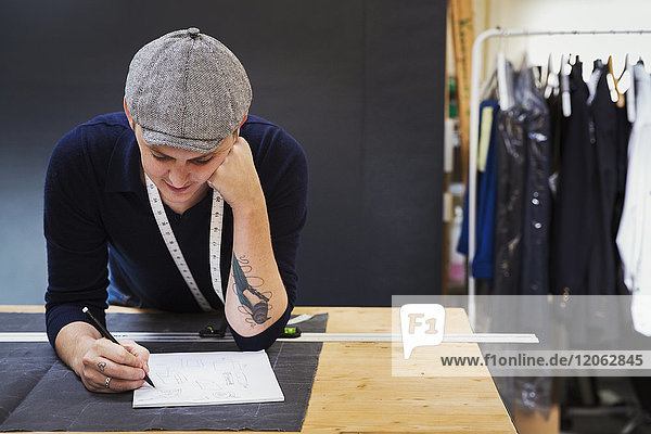Ein Mann an einer Werkbank  der mit Bleistift und Papier zeichnet und ein Projekt plant.