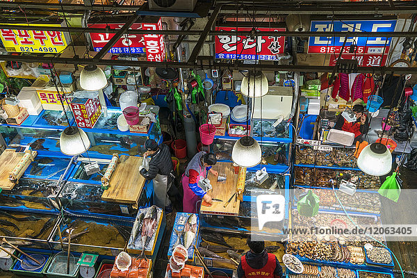 Schrägansicht auf Verkäufer  die an bunten Marktständen auf dem Fischmarkt arbeiten.