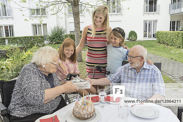 Familie feiert den Geburtstag der Großmutter im Hof des Altenheims