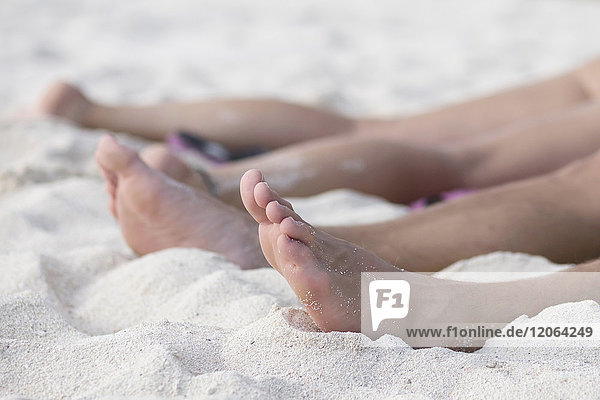 Niedriger Ausschnitt eines Paares beim Entspannen im Sand