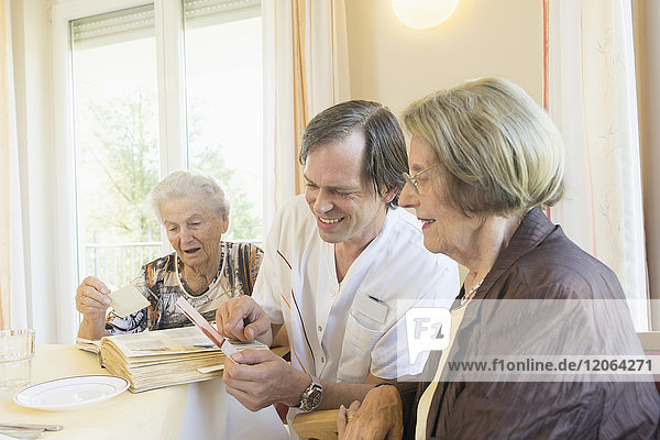Betreuerin sieht sich Fotos mit älteren Frauen im Altersheim an