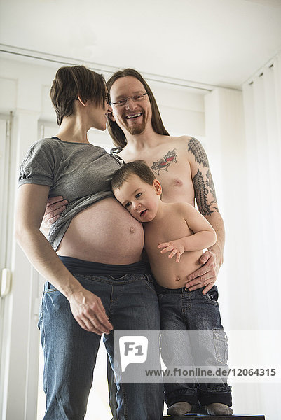 Eltern mit kleinem Jungen hören auf den Bauch der schwangeren Mutter