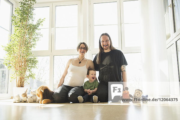 Porträt einer glücklichen Familie mit schwangerer Mutter  die zu Hause sitzt